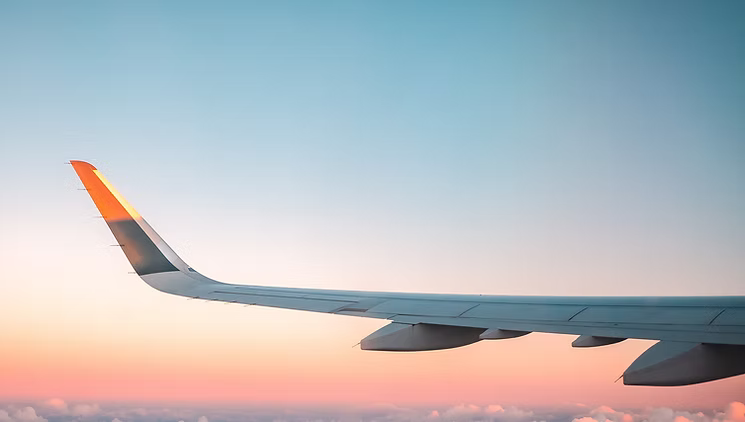 Airplane wing over a sunset, viewed through the window